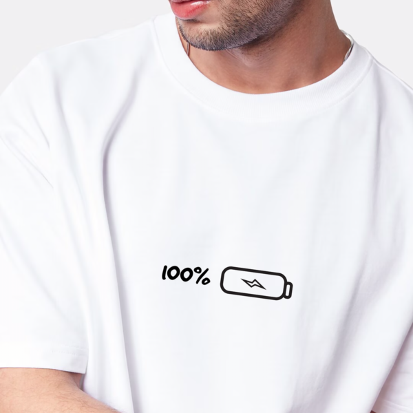 A stylish boy wearing an oversized round neck white t-shirt featuring a 100% battery which means fully charged design