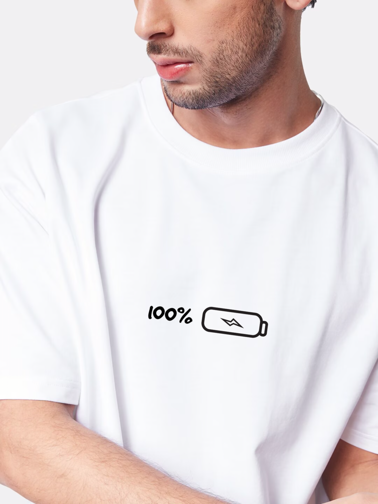 A stylish boy wearing an oversized round neck white t-shirt featuring a 100% battery which means fully charged design